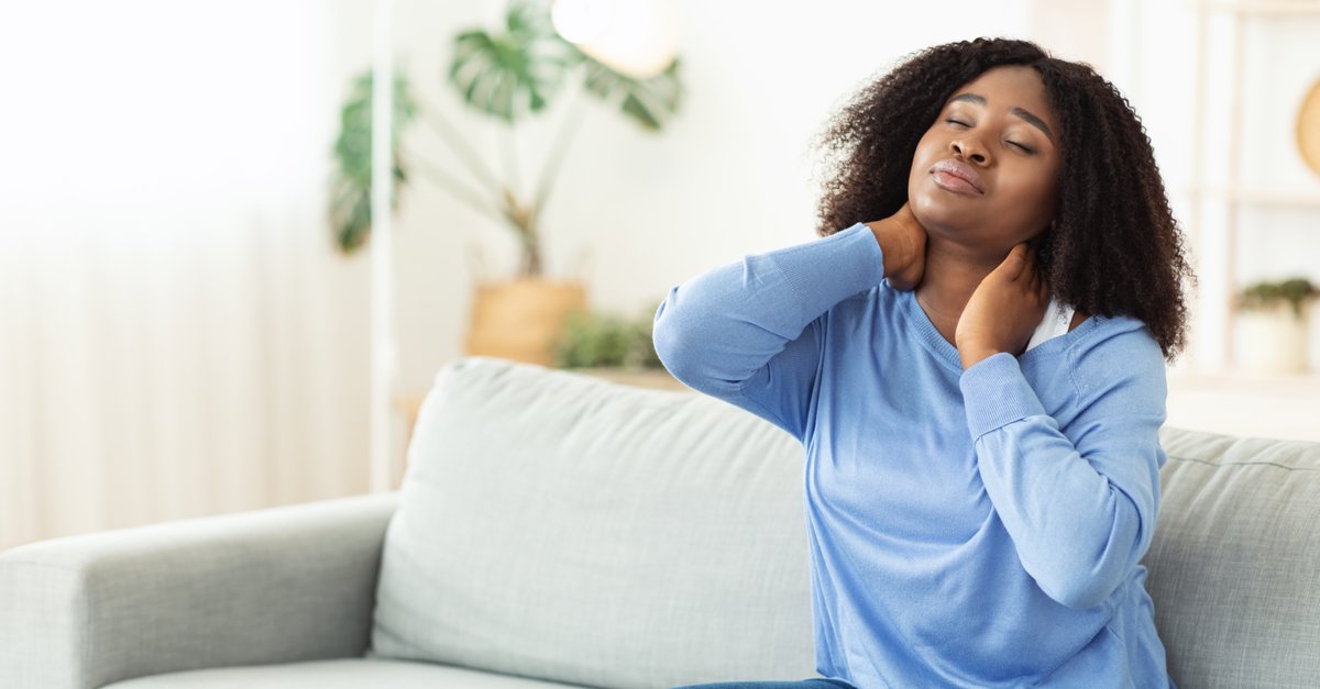 tired black woman sitting on sofa with neck pain-img (1)