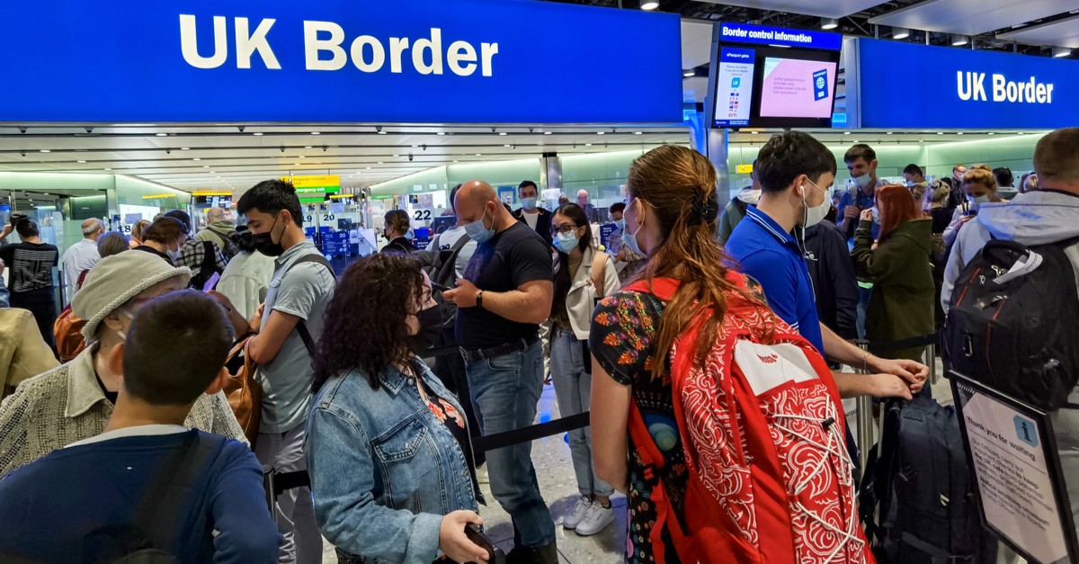 Air travelers with face mask queuing at UK border control-img