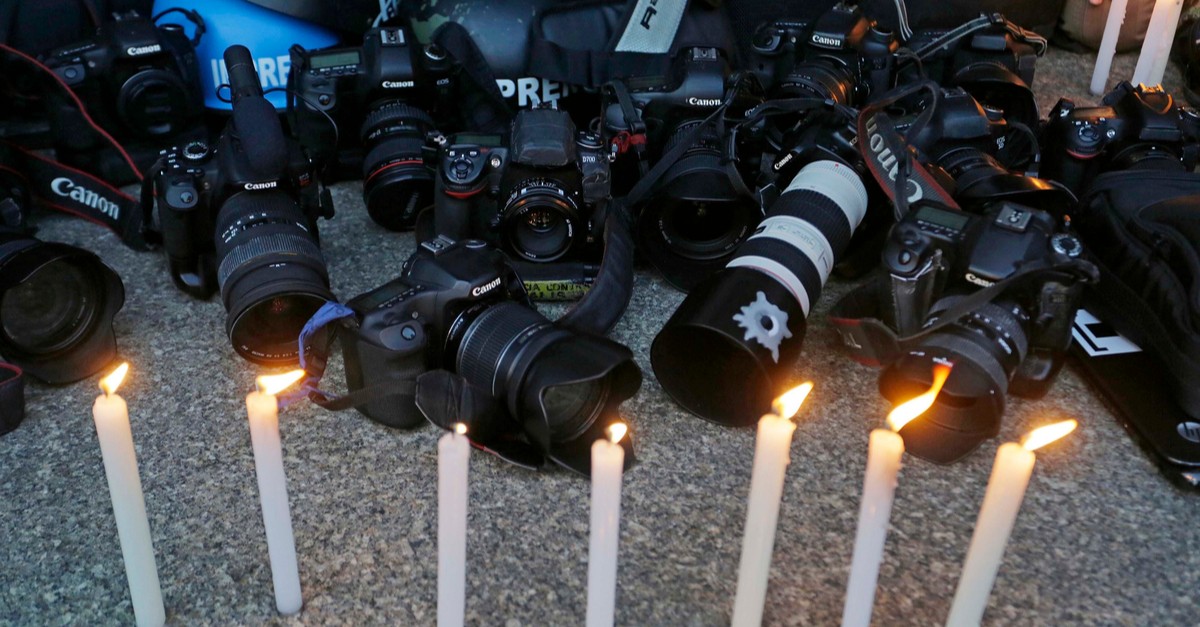Photojournalists light candles during a vigil -img