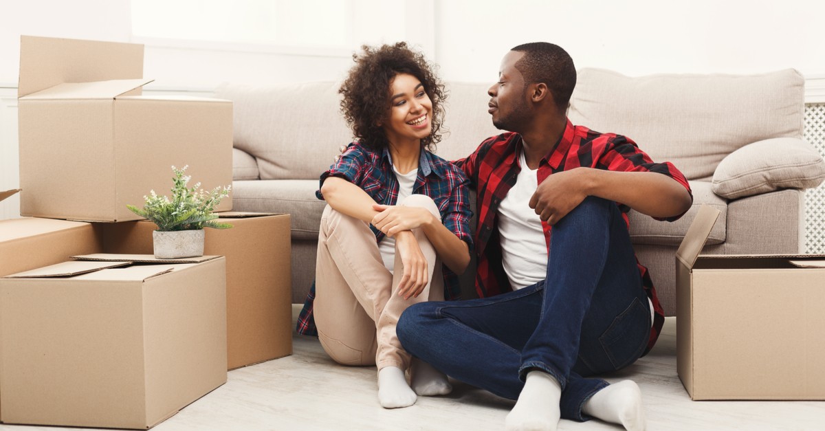 Happy african-american couple unpacking moving boxes in new apartment-img