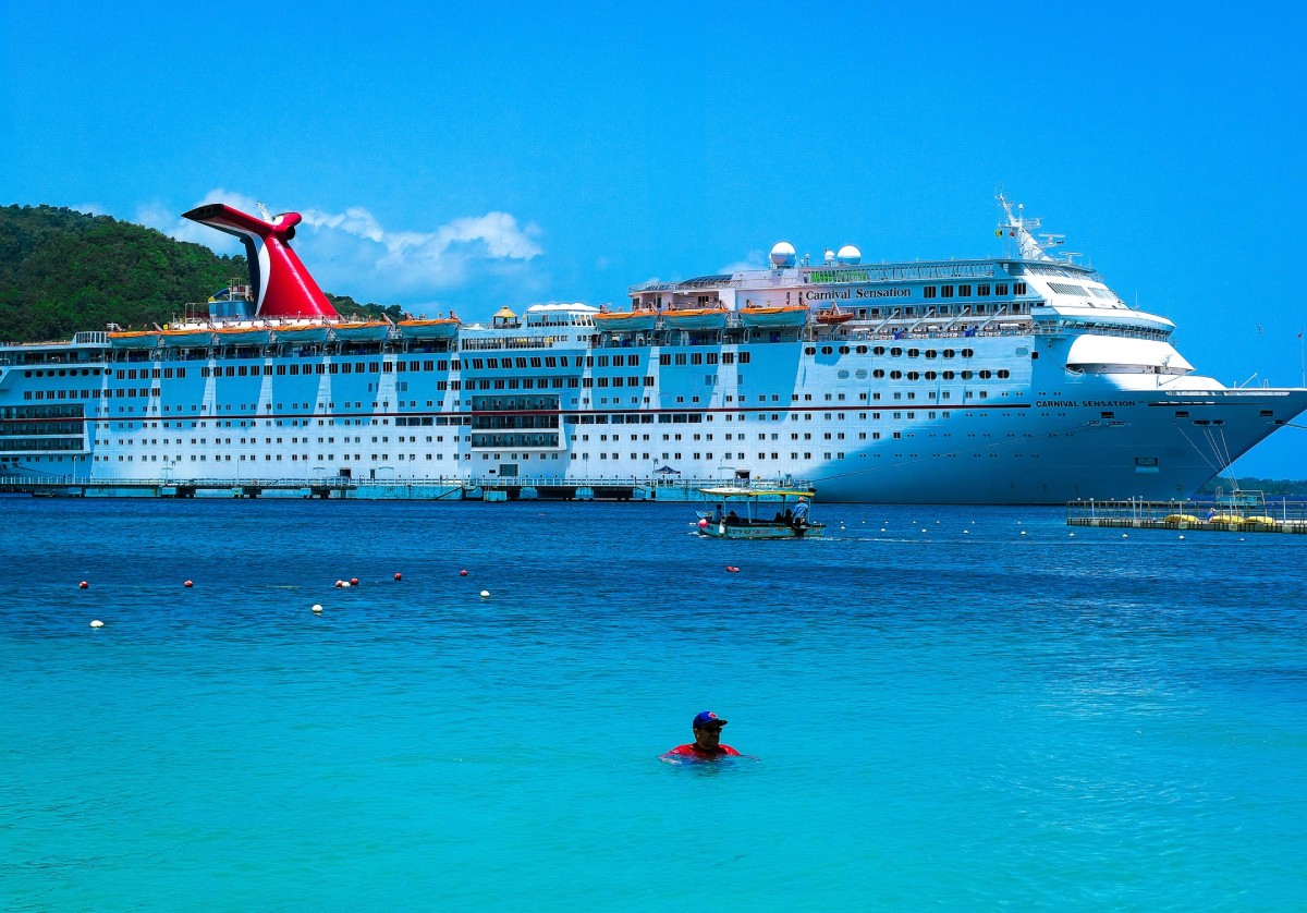 A man in red and blue floats in front of a docked Carnival Cruise Ship-img