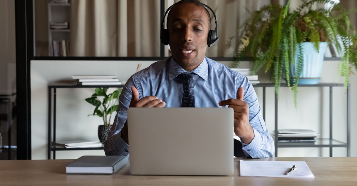 African American business man in headphones making work video call on laptop-img