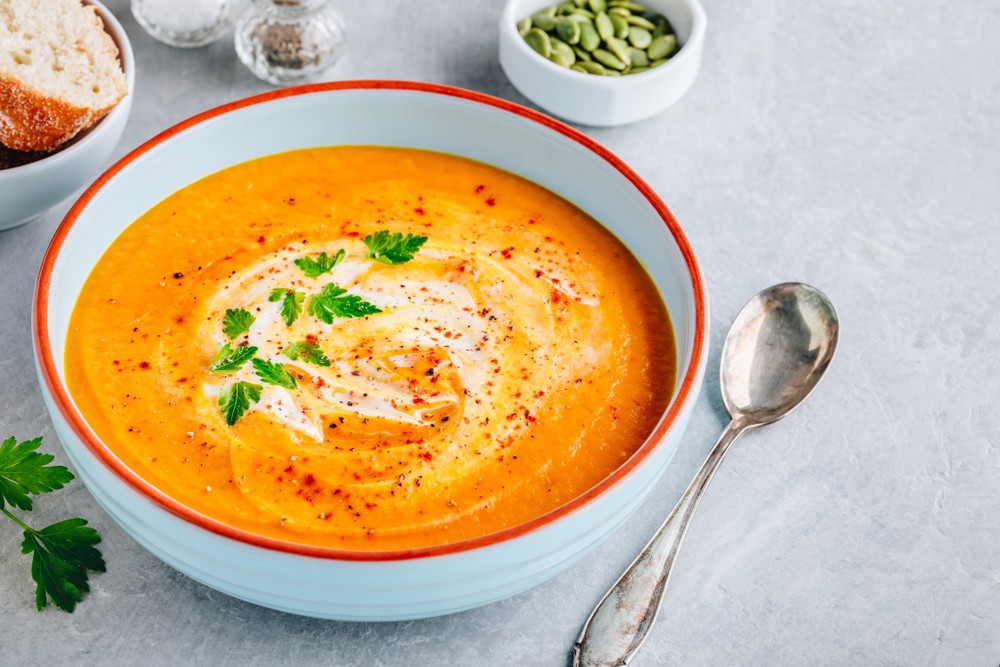 Carrot and pumpkin cream soup with parsley on gray stone background-img